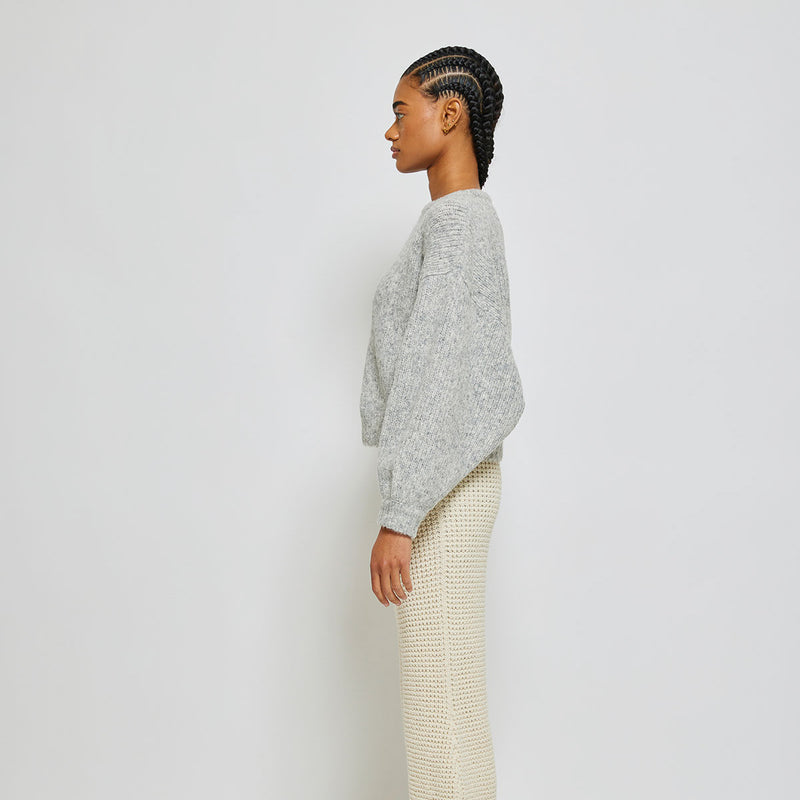 Person wearing light grey knit sweater on white background