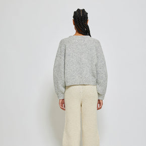 person wearing light grey knit sweater on white background