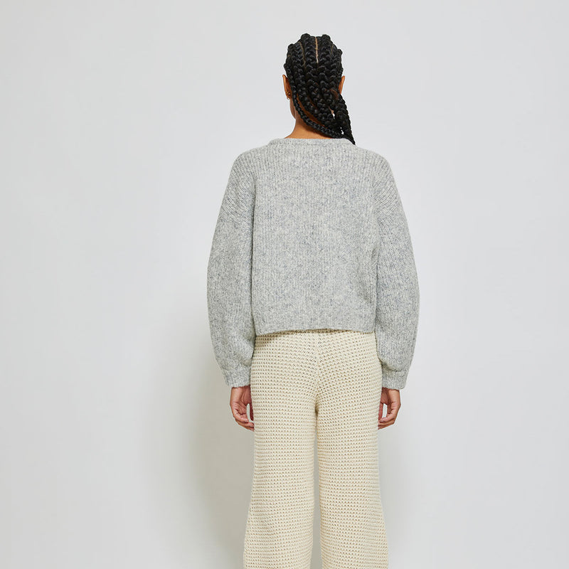 person wearing light grey knit sweater on white background