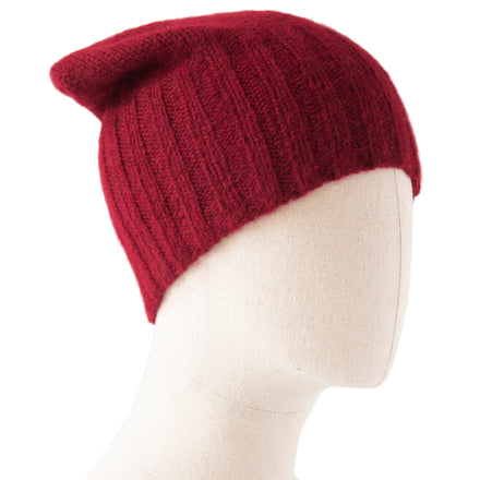 A red hand-knitted flat hat on a mannequin head.