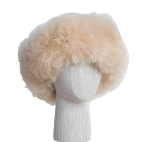 Premium Baby Alpaca Fur Hat. A beige Premium Baby Alpaca Fur Hat on a mannequin head against a white paneled background.
