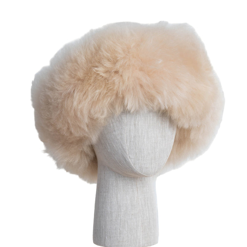 Premium Baby Alpaca Fur Hat. A beige Premium Baby Alpaca Fur Hat on a mannequin head against a white paneled background.