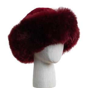 Premium Baby Alpaca Fur Hat. A Burgundy Premium Baby Alpaca Fur Hat on a mannequin head against a white paneled background.