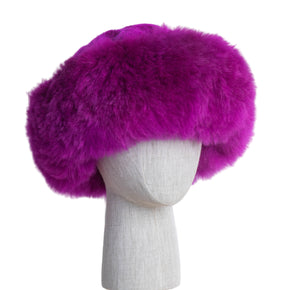 Premium Baby Alpaca Fur Hat. A fuchsia Premium Baby Alpaca Fur Hat on a mannequin head against a white paneled background.