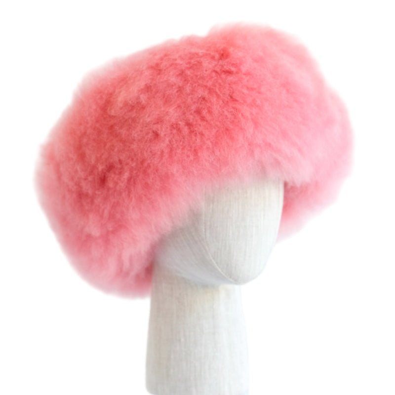 Premium Baby Alpaca Fur Hat. A pink Premium Baby Alpaca Fur Hat on a mannequin head against a white paneled background.