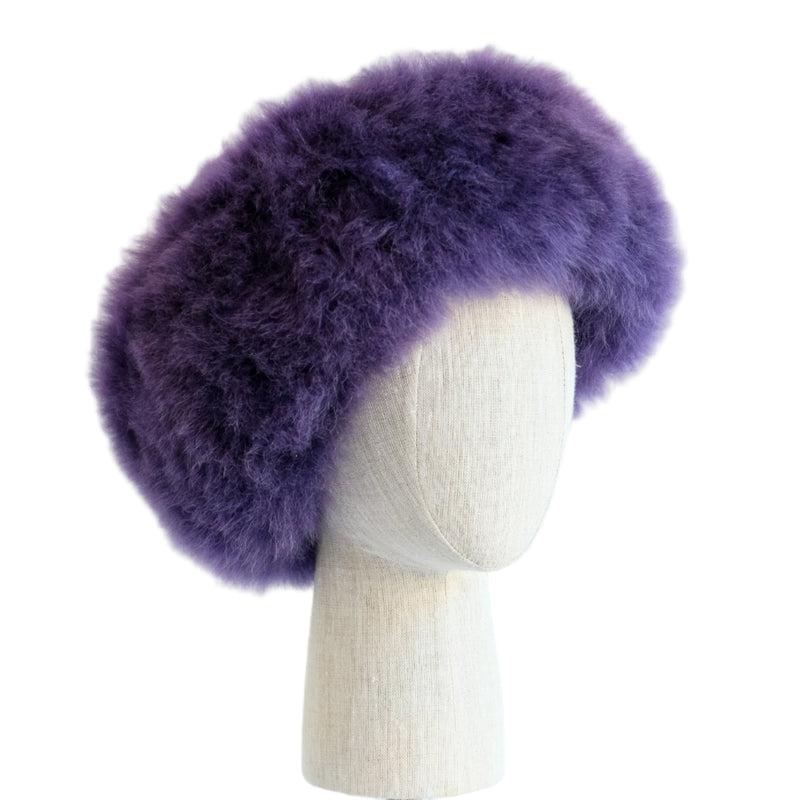 Premium Baby Alpaca Fur Hat. A purple Premium Baby Alpaca Fur Hat on a mannequin head against a white paneled background.