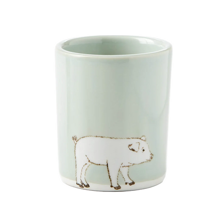 Ceramic mug with a pig illustration on a light green background