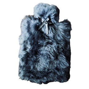 A hot water bottle cover made of alpaca fur and lambskin, predominantly gray in color, with a satin bow on the front.