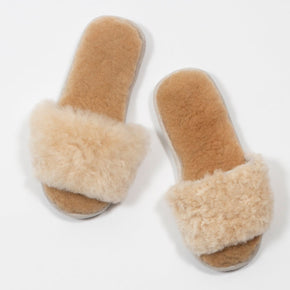 Pair of tan slippers with fluffy fur on a white background